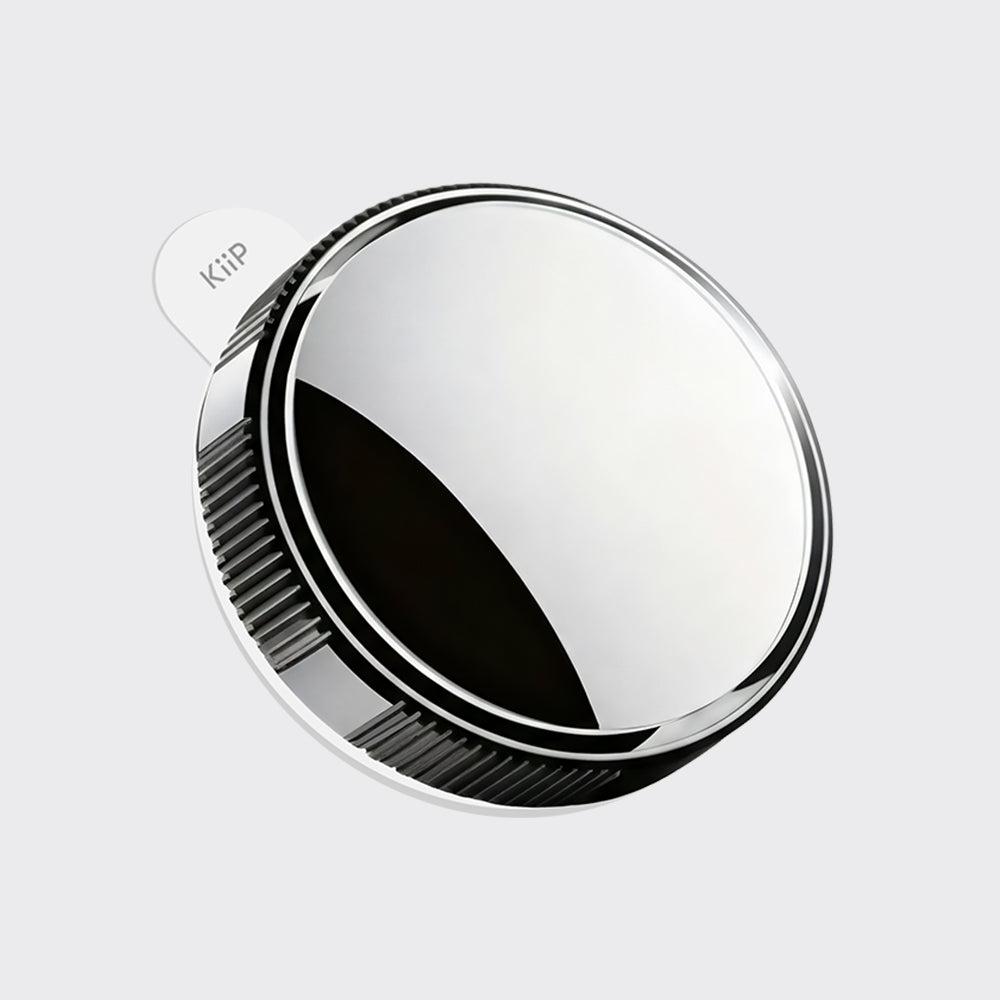 A round, polished silver metal accessory with a ribbed outer edge and a small white tab printed with the brand name 'KiiP', shown on a light gray background.