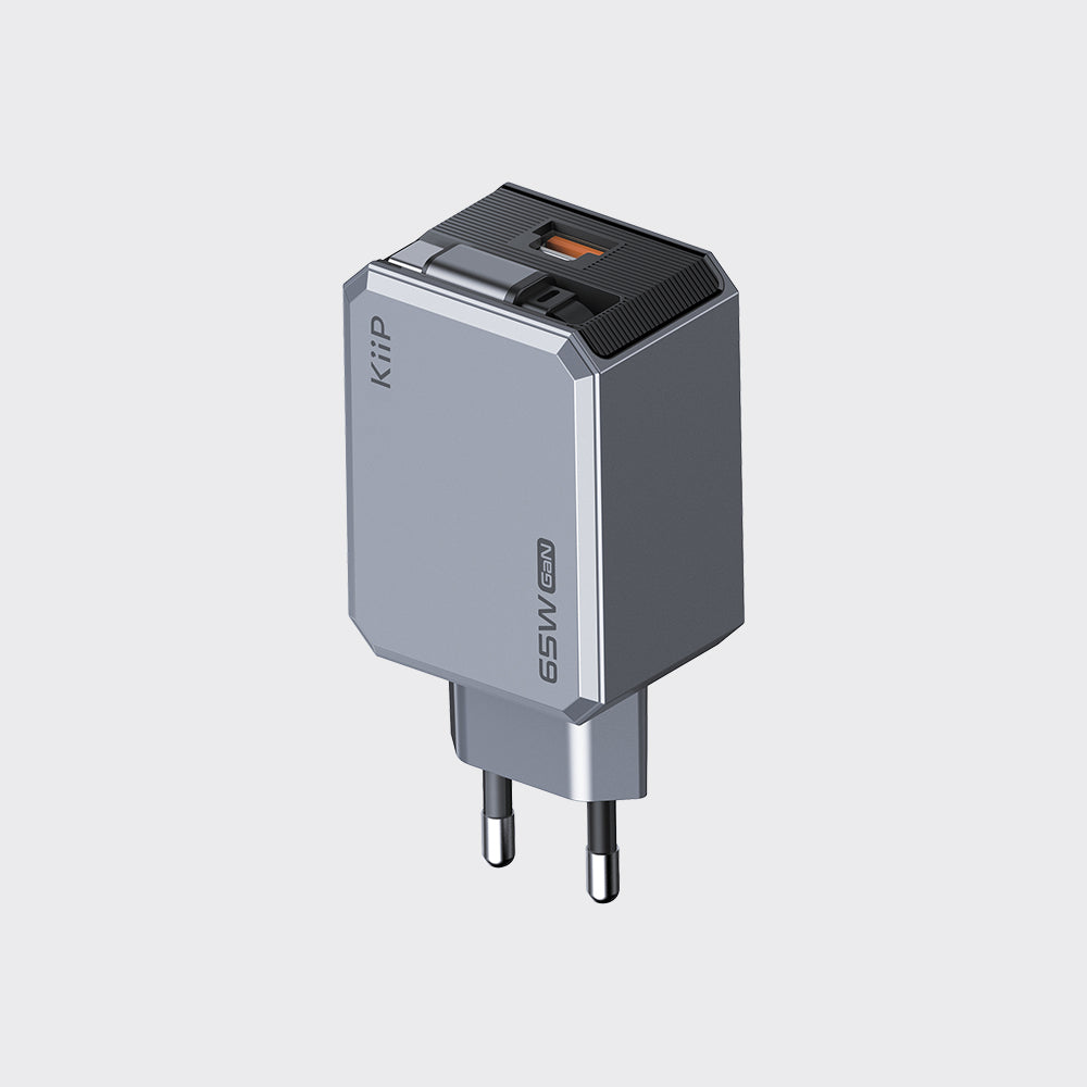 A compact 65W USB-C wall charger with a gray and silver metallic body, a black top cover, and a European plug, shown on a light gray background.