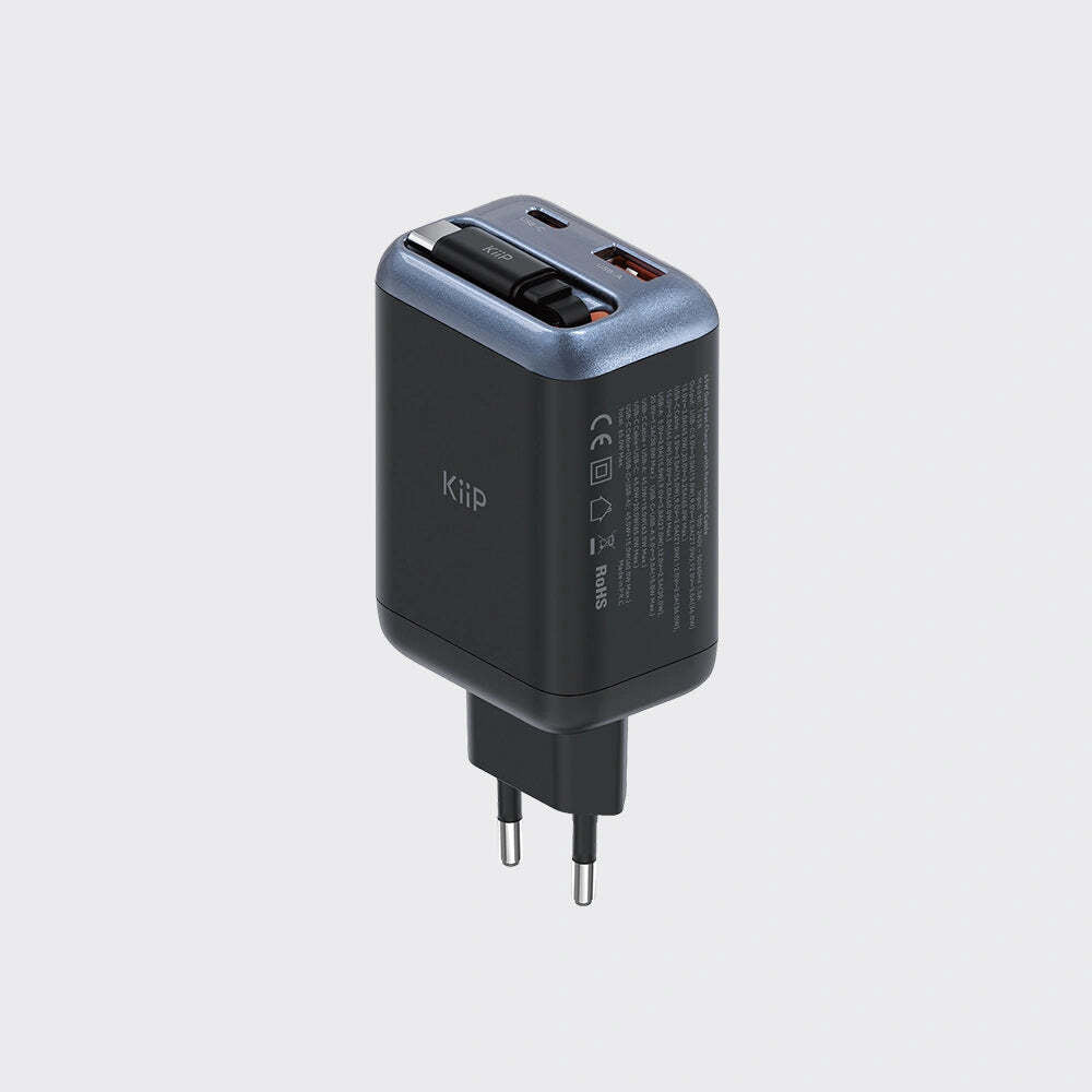 A compact black and slate blue KUP travel power adapter with a European plug, shown on a light gray background.