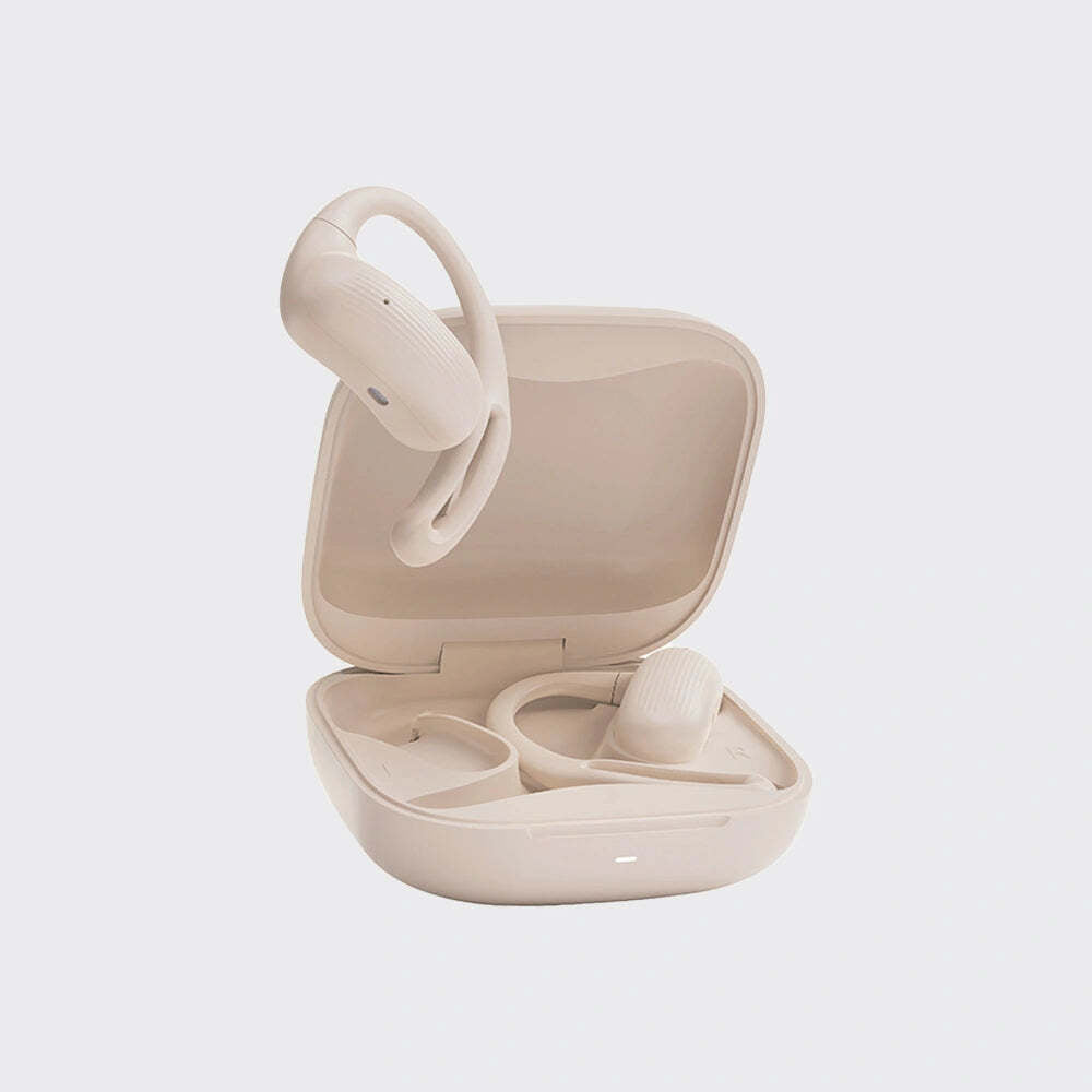 A pair of beige wireless ear hooks with an open matching charging case on a light gray background.